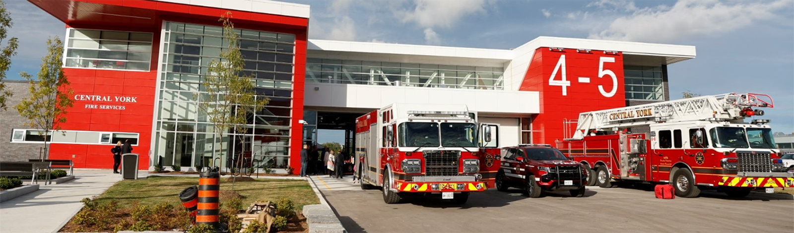 Front of 4-5 fire station with fire trucks in front, on a sunny day