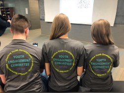 3 youth showing off the back of their youth engagement t shirts
