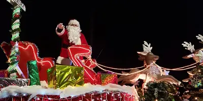 Santa Claus on sled with reindeer at night time parade