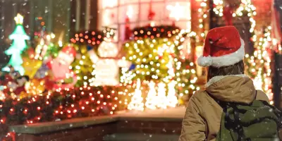 Woman wearing Santa hat look at Christmas outdoor lights on house