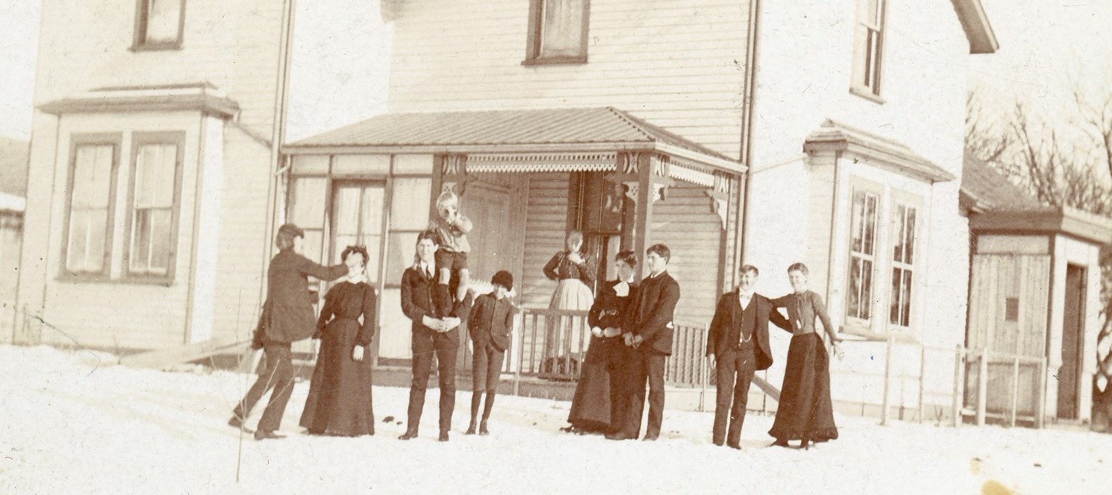 Very old picture with people standing in front of a house