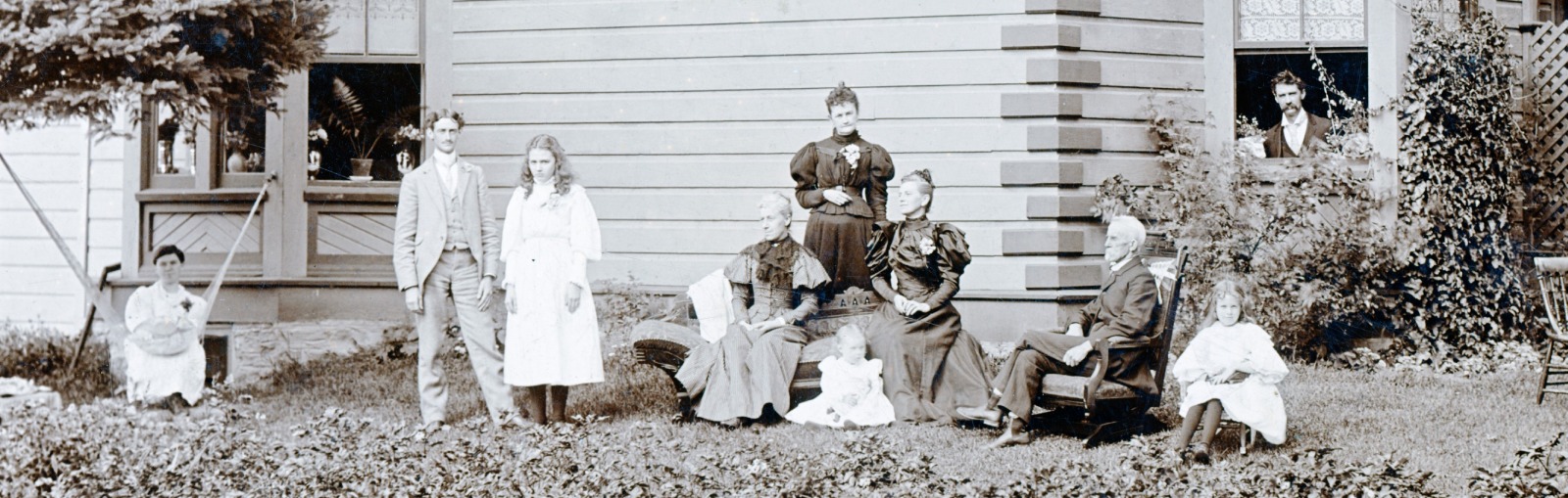 Black and white photo of a family posing outside their home.