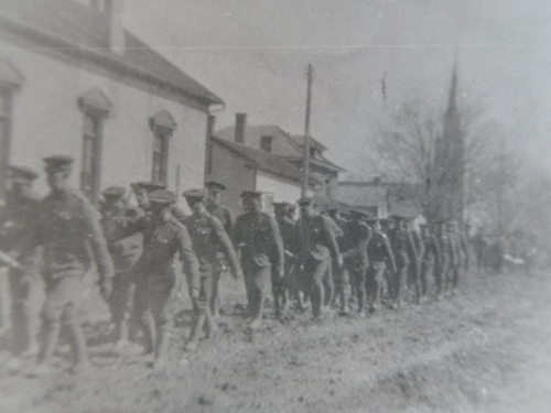 Black and white photo of soldiers marching on a muddy road during the First World War.