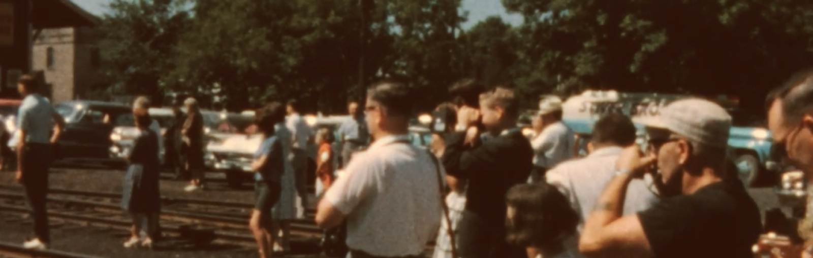 People lined up on train tracks holding cameras. 