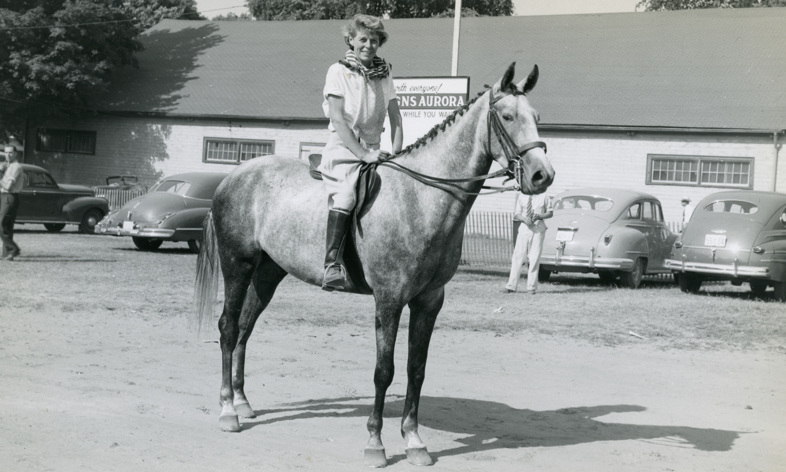 A black and white image of a woman on top of a horse, participating in the Aurora Horse Show, Town Park, 1948.