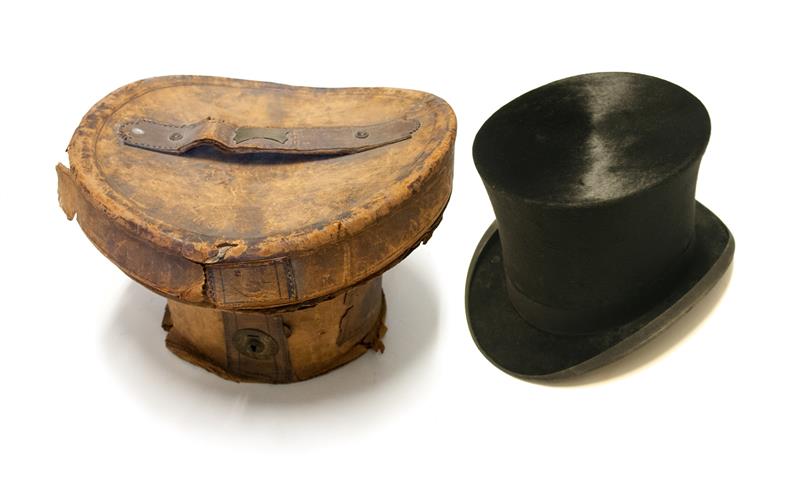 A tan coloured top hat box and black top hat from 1905. 