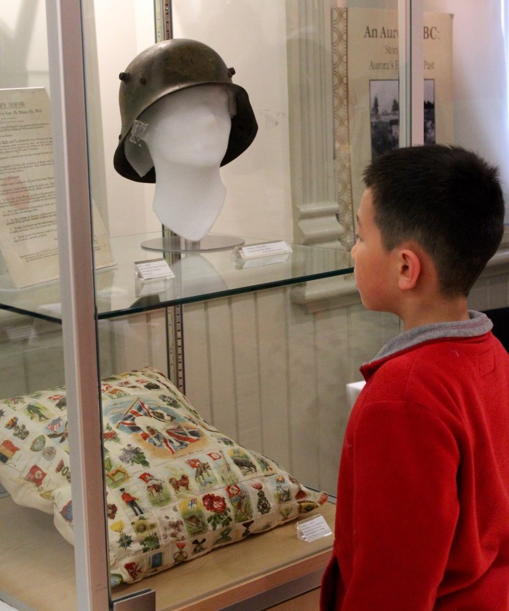 Colour photo of a display case with a boy looking into it. 