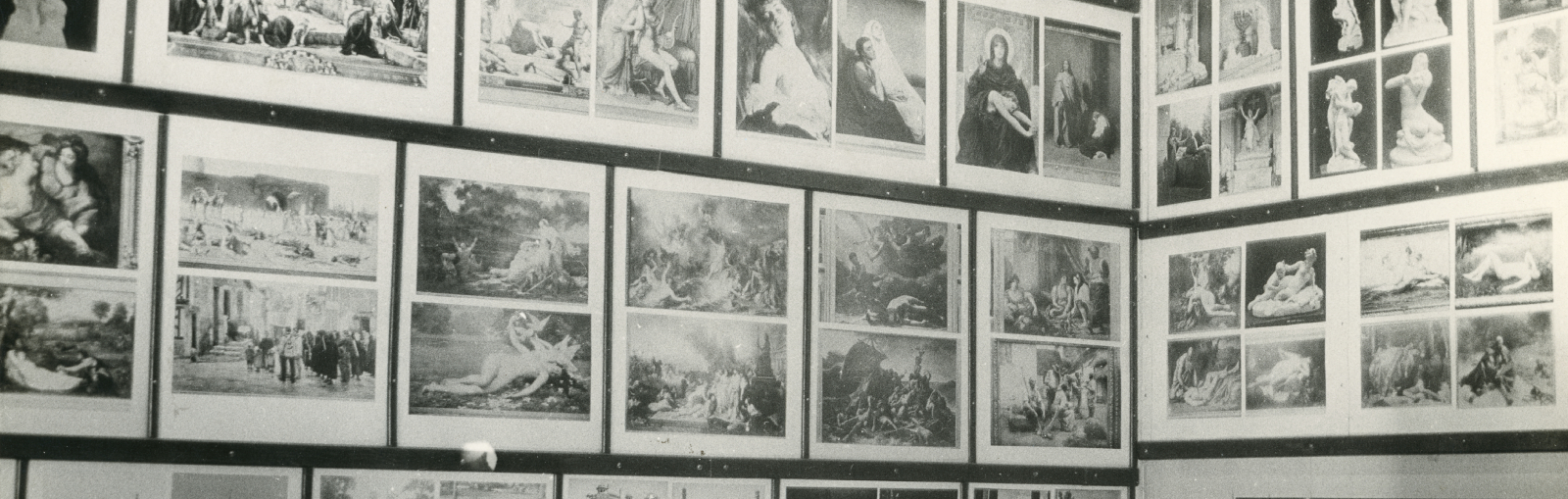 Black and white photo of a room populated with photos of famous art and sculptures. 