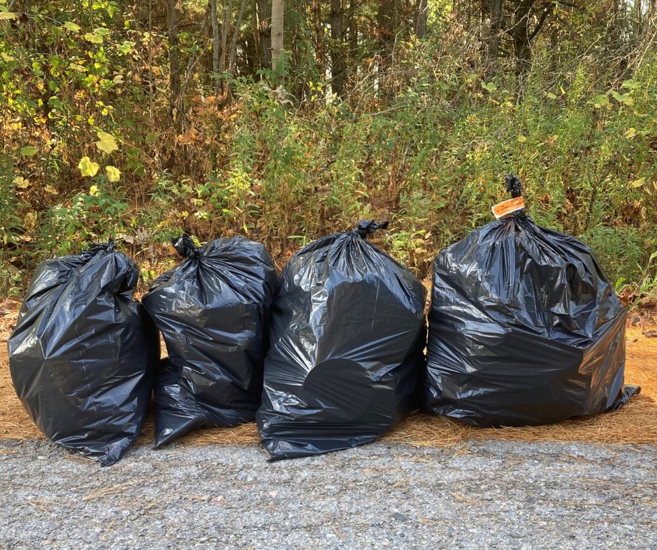 Image of four black garbage bags one with a bag tag on it