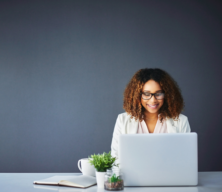 Smiling woman sitting at a desk looking at her laptop