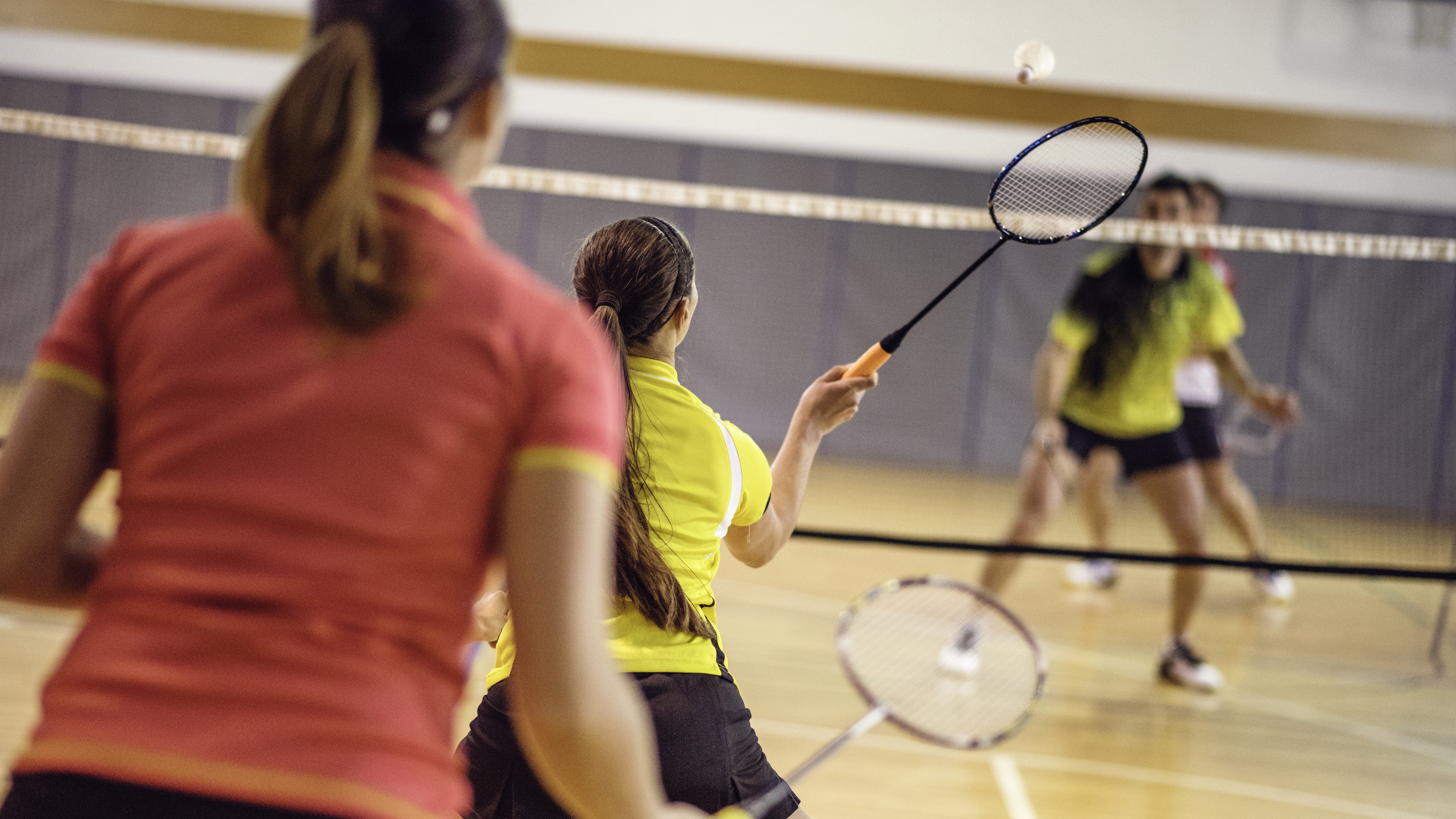 Four adults playing badminton