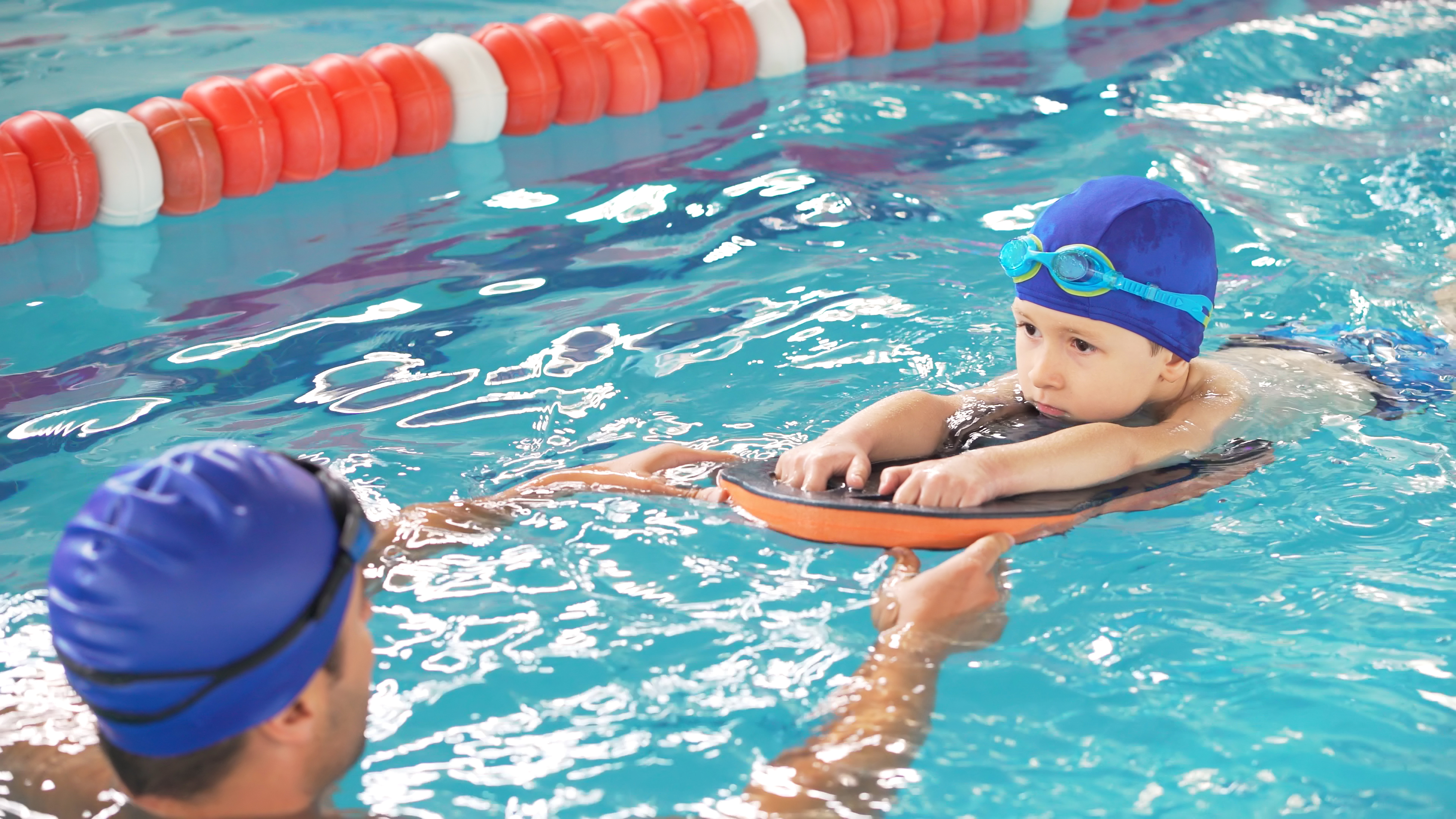 Male swim instructor and child in water