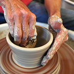 Hands demonstrating throwing a pot
