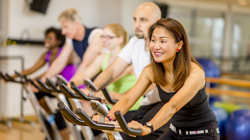 Group of adults on indoor cycling fitness bikes
