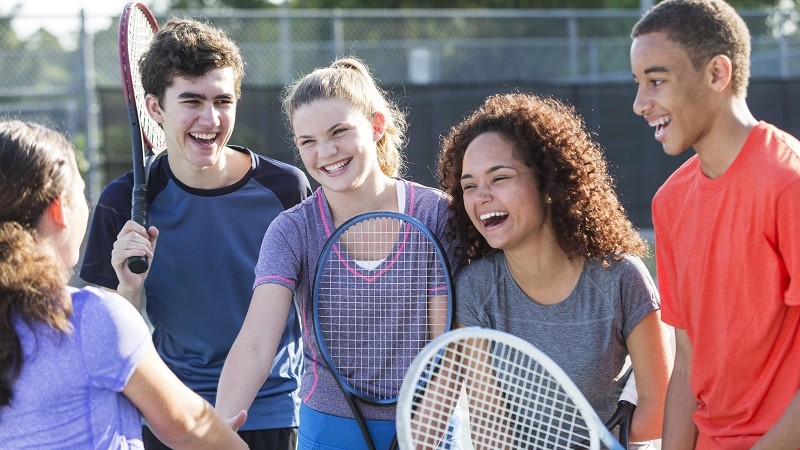 Teens playing tennis on court