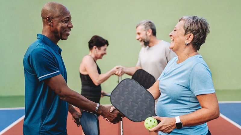 Two adult couples playing pickleball