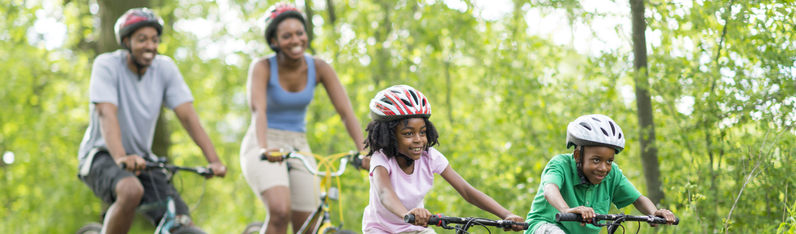 Family riding bikes along pathway in summer