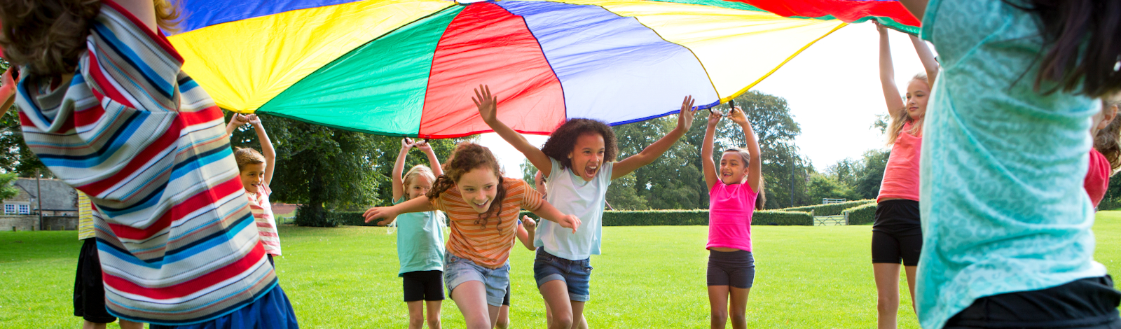 Kids running outside under parachute