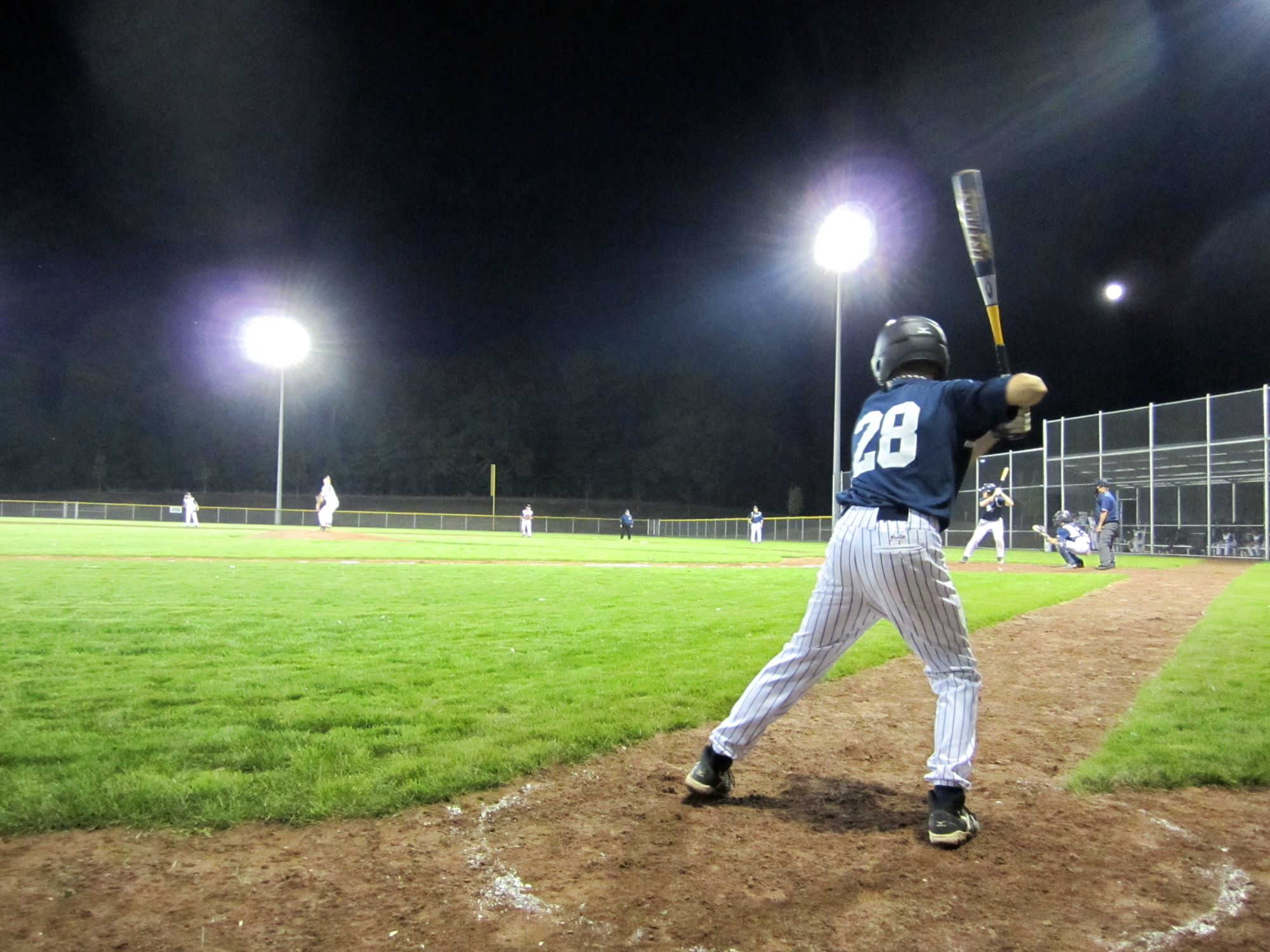 Person playing baseball at night on a field