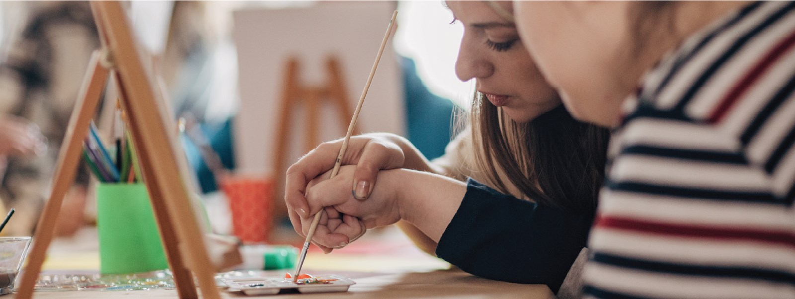 A person holding a child's hand, helping them paint