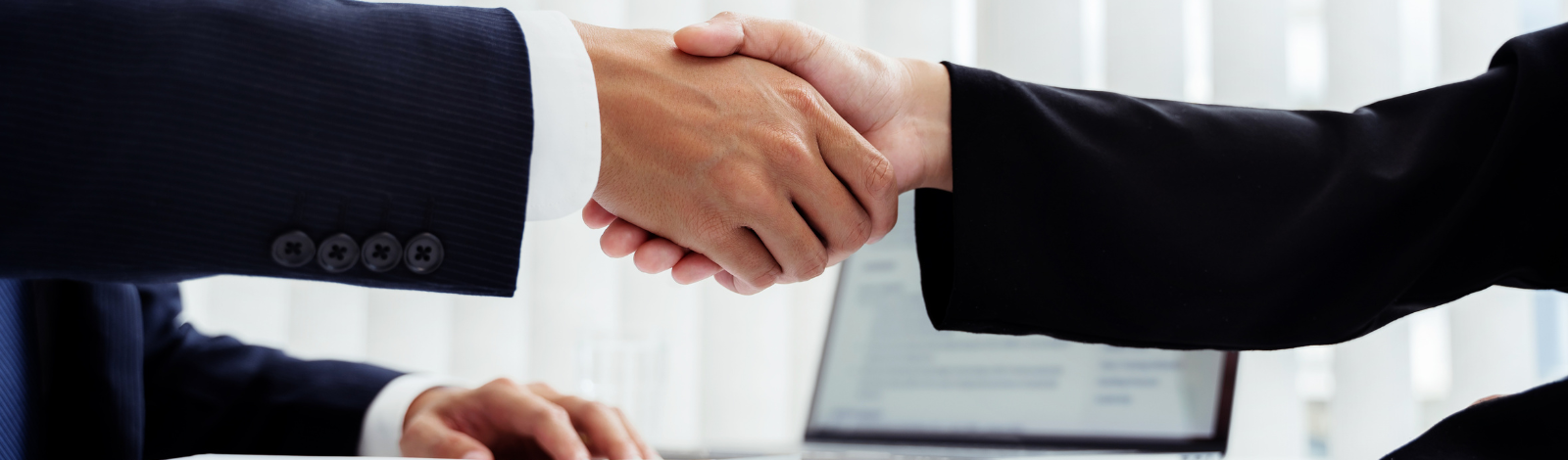 Two people shaking hands wearing suits