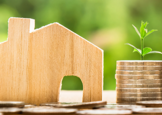 Mini wood house with coins beside it