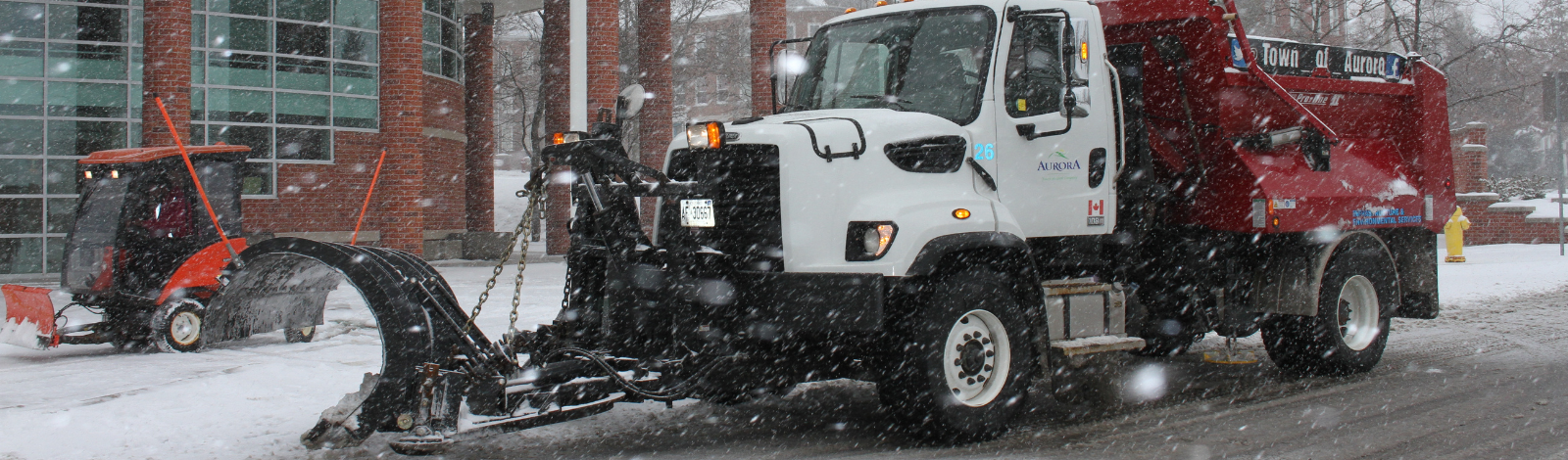 Town of Aurora snowplow shoveling snow outside Town Hall