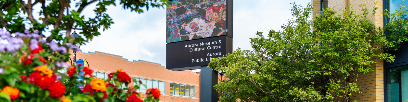 Large flower planter and the Aurora Museum & Cultural digital display at Church and Yonge Street