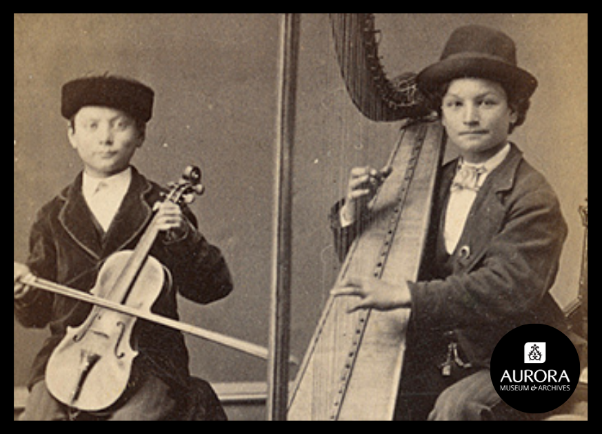 Very old image of two people in suite, one playing the harp and the other one the violin