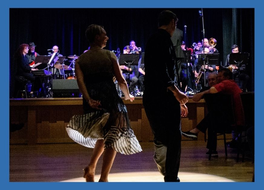 Man and woman with backs to the camera dancing on a stage