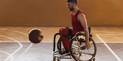 Man in wheelchair playing basketball in gymnasium
