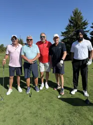 Five men on a golf course, four holding golf clubs