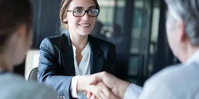 A person shaking hands with a woman in a suit