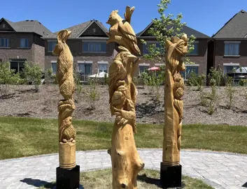 Three wooden poles carved into wildlife animals, turtle, bunny, bear