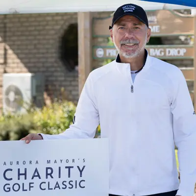 Mayor holding golf poster
