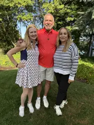 A man and two women, standing on either side of the man, posing for a picture