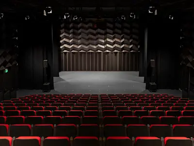 Inside of a theatre, showing red theatre seating and stage at ground level