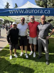 Four men, side by side, in front of a tent and posing for a picture