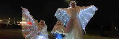 Three ladies wearing glow in the dark lit up Christmas themed clothes at Santa parade event
