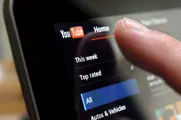 Finger near a screen with the YouTube logo