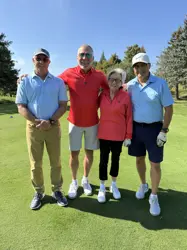 Three men and a woman standing on a gold course