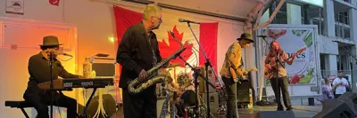 Musical band on stage singing and playing instruments with Canada flag on display