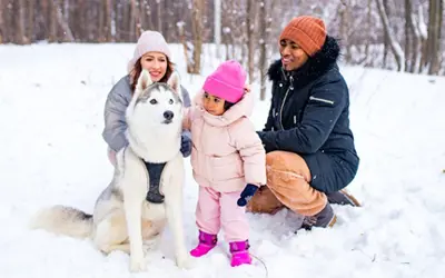 Dad, mom and daughter with dog in snow