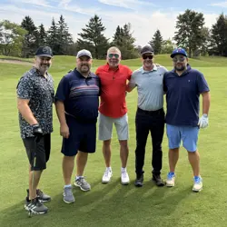 Five men on a golf course, one holding a golf club