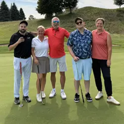 Two men and two women on a golf course, four holding golf clubs