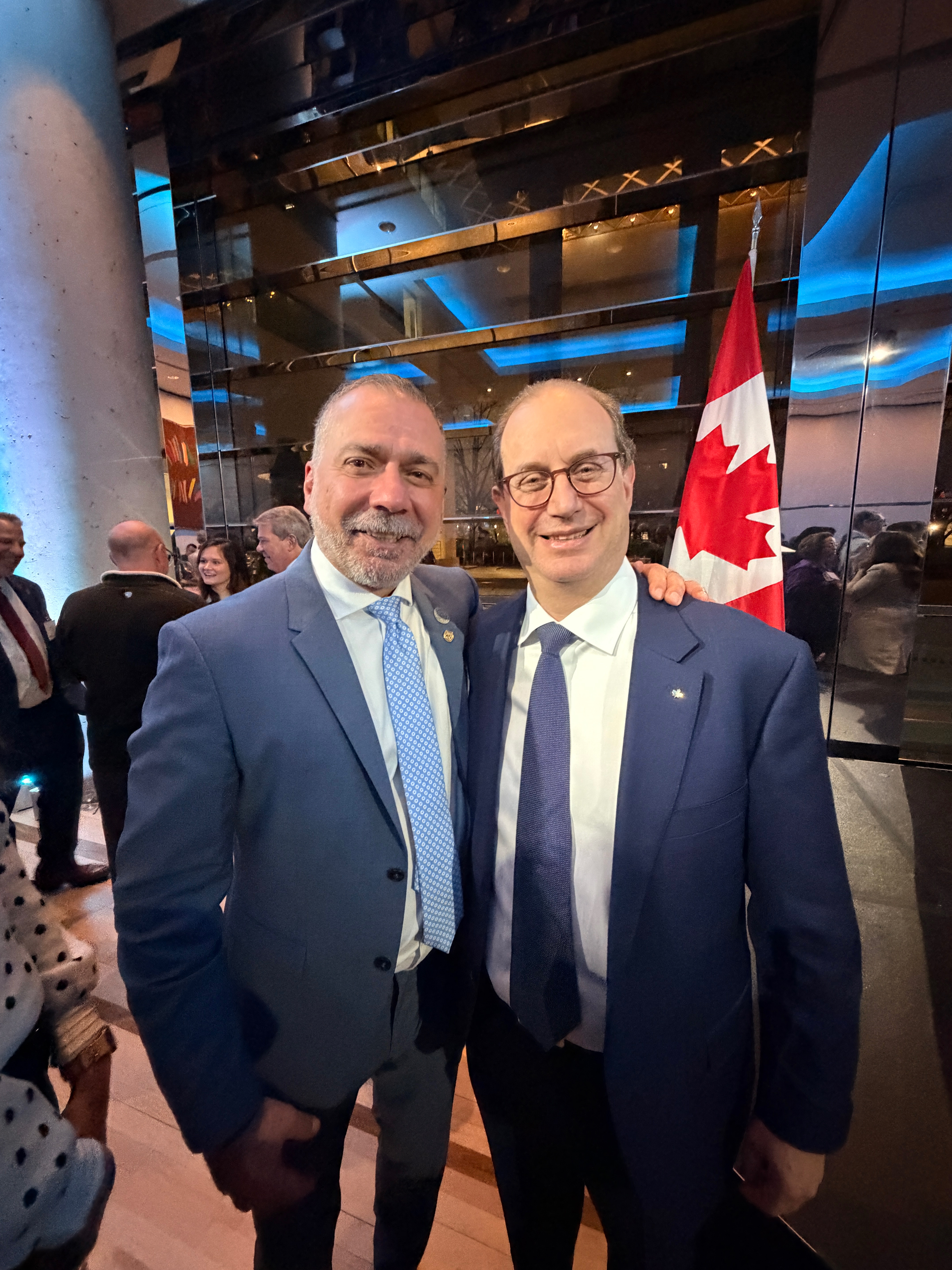 Mayor standing beside a gentleman with the Canadian flag behind