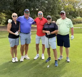 Four men and a woman on a golf course, four holding golf clubs