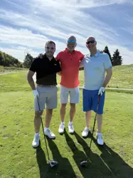 Three men on a golf course, two holding golf clubs