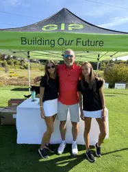 One man and two young girls standing in front of a large tent