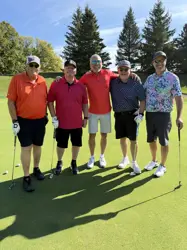 Five men on a golf course, four holding golf clubs